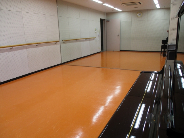 アップライトピアノとレッスンバー、一面の鏡張りが写っているリハーサル室の写真