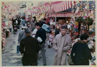 飾り付けされた屋台で賑わう道を通行人たちが行きかっている写真