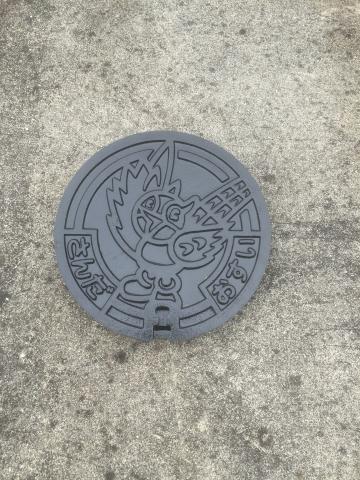 マスコットのキッピーが刻印されている小さな公共マスの蓋の写真