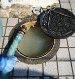 マスの蓋を外し溜まった汚水にホースを差し込む様子の写真