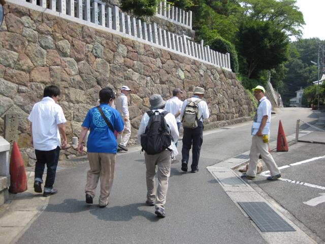 石造りの壁の横の坂道を歩く人々の写真
