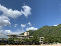 広い青空と緑の山に囲まれる高平小学校の写真