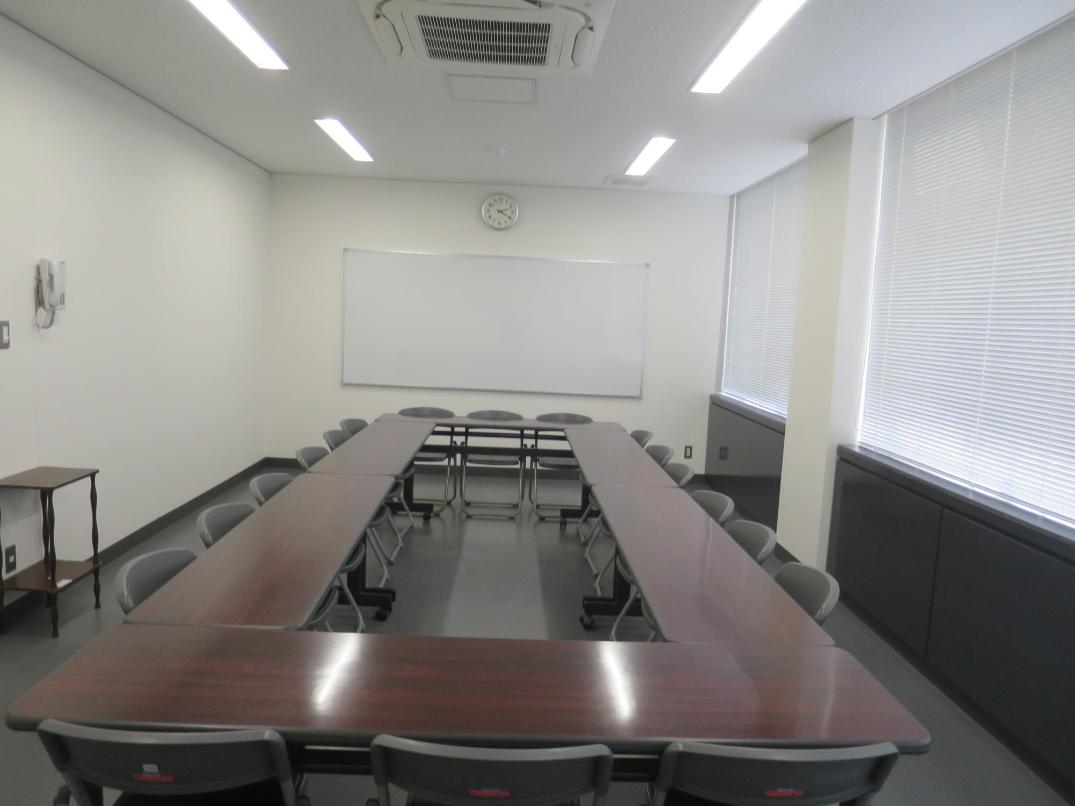 ホワイトボードに向かって右手に窓、長机で四角く囲み椅子を並べた2階小会議室1を写した写真