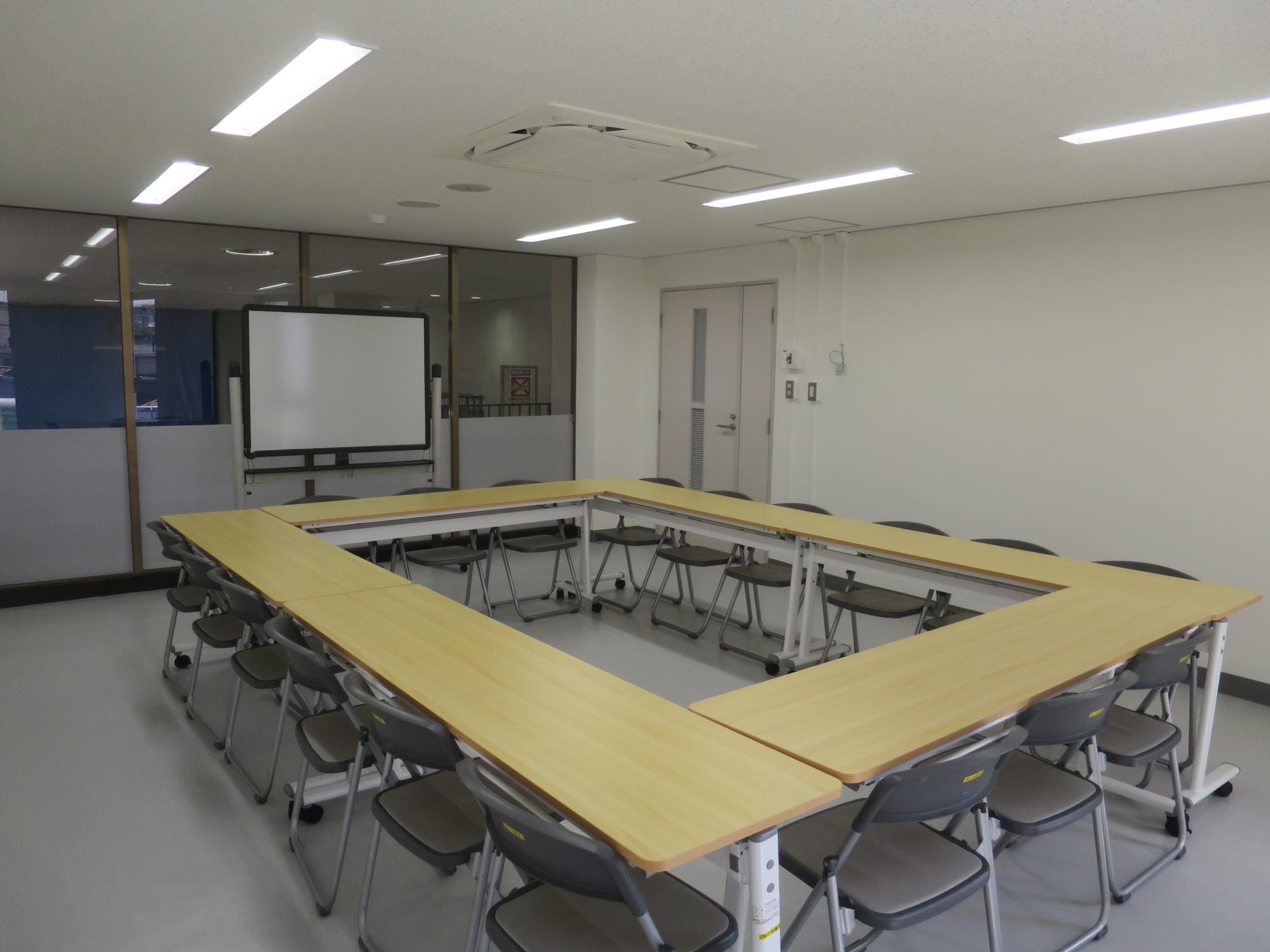 長机で四角く囲みその周りに椅子を18脚並べた2階小会議室2の写真