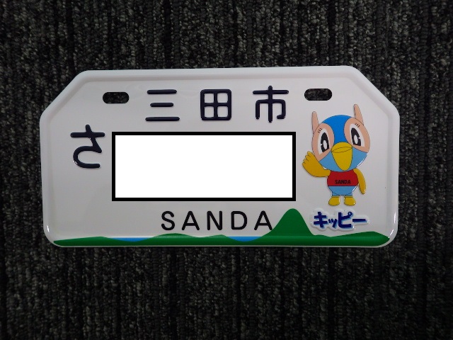 三田市マスコットキャラクター「キッピー」の絵があしらわれた、原動付自転車用ナンバープレートのサンプル写真