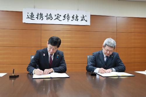 協定書に署名をする野上会長と田村市長