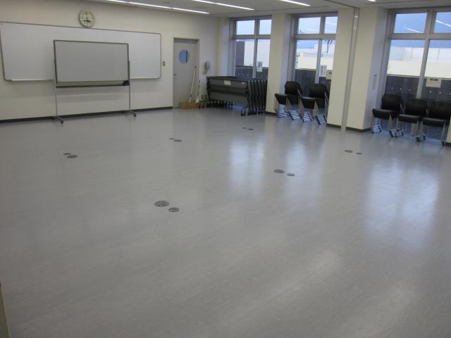 スクリーンとホワイトボード、窓側に整理された机と椅子を写した会議室1の写真