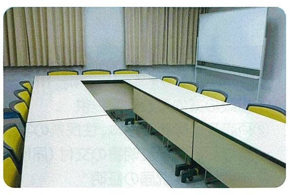 テーブルを囲みその周りに椅子を並べた様子を写したミーティングルームの写真