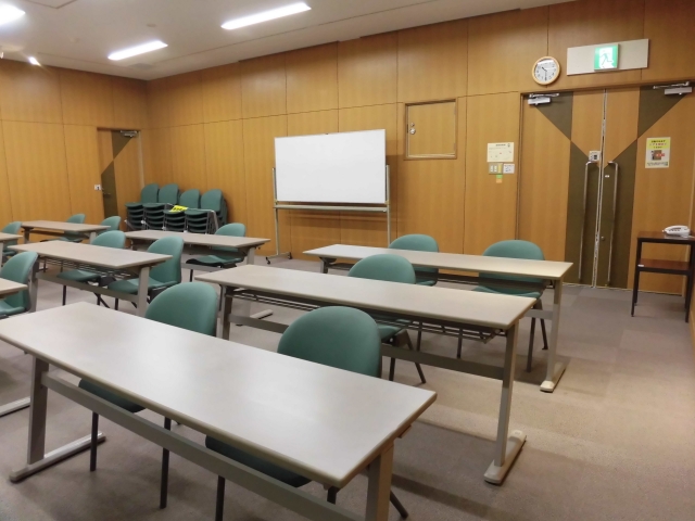 奥にホワイトボード、中央にテーブルと椅子が並べられた大会議室(後室)を前方から写した写真