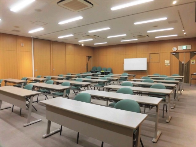 手前に机と椅子、中央奥にホワイトボードがある大会議室(全室)を前方から写した写真