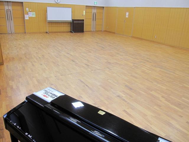 前方に電子ピアノ、後方にホワイトボードが写った多目的室の写真