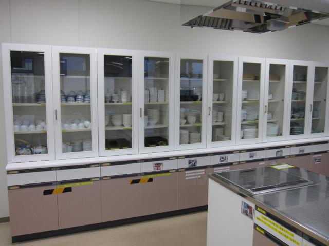 背の高い棚に様々な食器が収納されている様子を写した調理室の写真