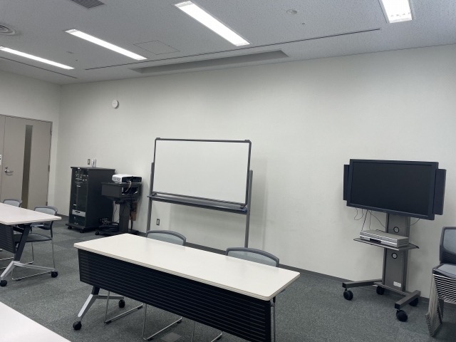 左に音響設備、中央にホワイトボード、右に映写設備が配置された講座室を写した写真