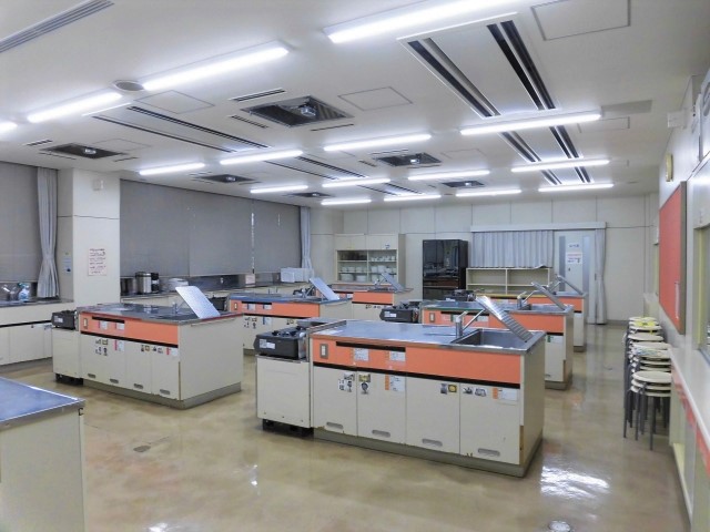 奥に食器棚や冷蔵庫、中央に調理台が並べられた調理室を前方から写した写真