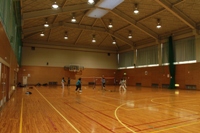 6名の男女がバレーボールに興じている勤労者体育センター（体育館）の写真