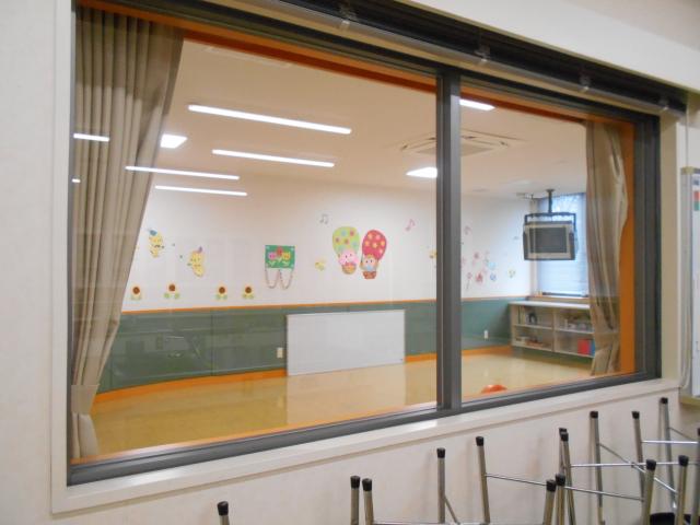 窓を挟んで向こうに幼児室がみえる調理室を写した写真