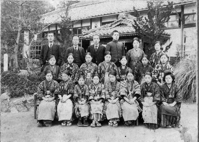 和服の女性たちとスーツ姿の男性が列をつくって並んでいる、中野村農業補修学校女子部の白黒の記念写真