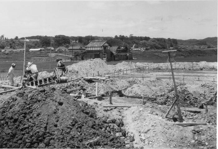 掘り起こされた土があちこちに積まれている、昔の工事現場の白黒写真