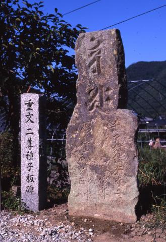 青空と山間を背景に撮影された「上槻瀬の板碑」の写真