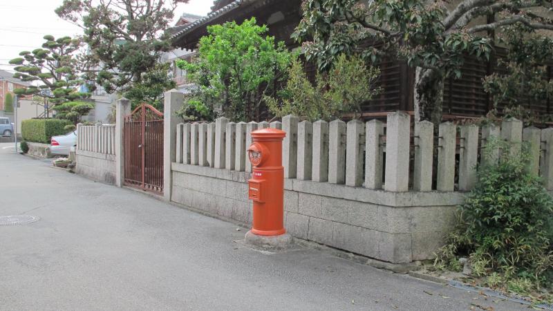 神社の近くに設置されている丸型ポストの写真