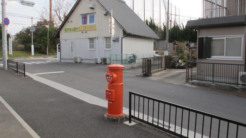 ガードレールと道路のすぐ傍に設置されている丸型ポストの写真