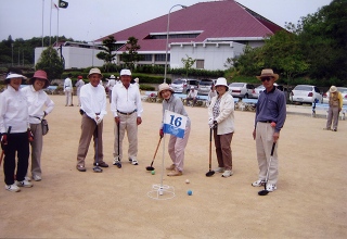 グラウンドでカメラのほうを向きながらゴルフクラブを構えるメンバーの写真