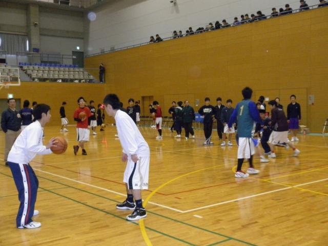 体育館内でバスケットボールのパス練習などを行うメンバーたちの写真