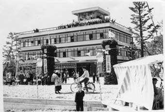 自転車に乗った人や通行人が行きかう建物周辺の写真