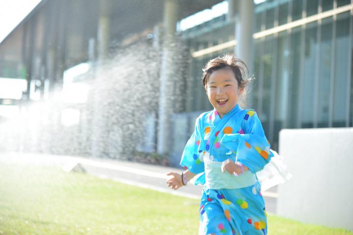 平成30年におこなわれた第40回三田まつりで市役所前風の広場で水色にカラフルなドット柄の浴衣姿の少女が楽しそうに走っている写真