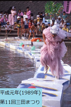 平成元年におこなわれた第11回三田まつりでピンク色のドレスの裾をたくし上げ発泡スチロールで作ったいかだ渡りをしている男性の写真