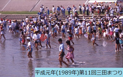 平成元年におこなわれた第11回三田まつりで川に入って魚の掴み取りをする網を持った大勢の子どもらの写真