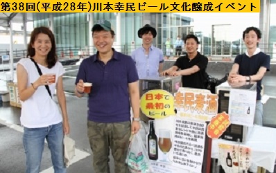 平成28年の第38回三田まつりの市役所前風の広場で川本幸民ビールが入ったプラスチックカップを右手に持ち笑顔を浮かべる女性と右横の男性および後ろの男性関係者3人の写真