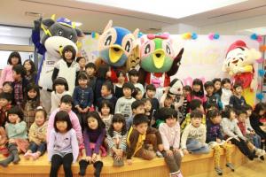 三田市にあるキッピーモール6階の舞台上で大勢の幼稚園児らに囲まれて記念撮影をおこなう左側のキッピーと右側のハッピーの写真