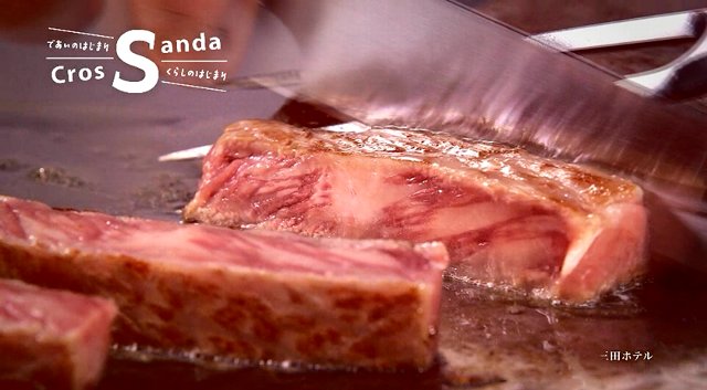 鉄板で焼かれた三田牛のステーキをミートフォークで押さえながらナイフで切った綺麗なサシが入っている断面の写真