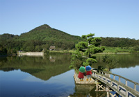 福島大池の上にかかる橋の先で寄り添いながら有馬富士を眺める左側のハッピーと右側のキッピーを背中側から撮影した写真