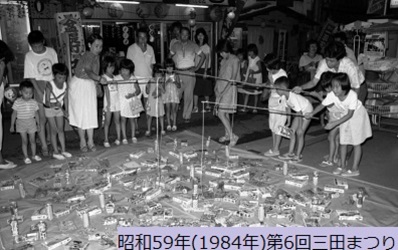昭和59年におこなわれた第6回三田まつりで子どもたちが欲しい景品を釣りあげようと、竿から垂れた糸を必死に景品にひっかけようと頑張っている写真