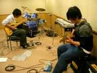 音楽スタジオで楽器を演奏する2人の若者の写真