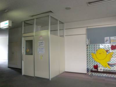 左側に中が暗いドアがあり、右側に黄色いウェアを着た赤ちゃんのイラストが描かれている建物の屋内の写真