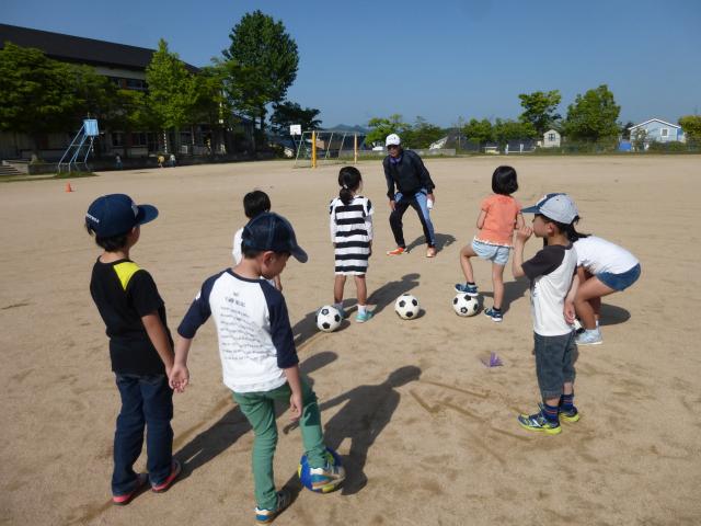 子ともたちがサッカーボールを蹴りながらサッカーを楽しむ写真
