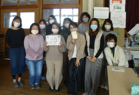 マスクをした11人の女性たちの室内での集合写真