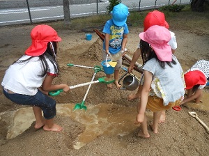 砂場で砂遊びをしている園児たちの写真