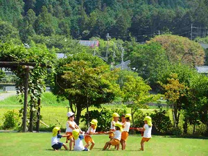 芝生の上で裸足で遊んでいる園児たちの写真
