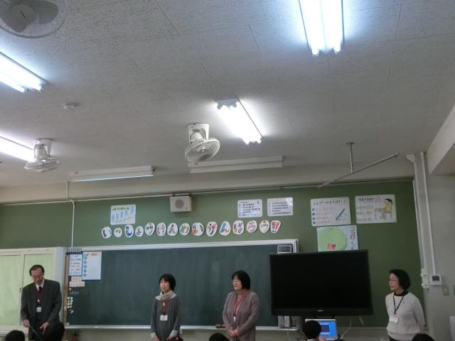 教室の黒板の前で男性と女性が間隔をあけて並んで立っている写真