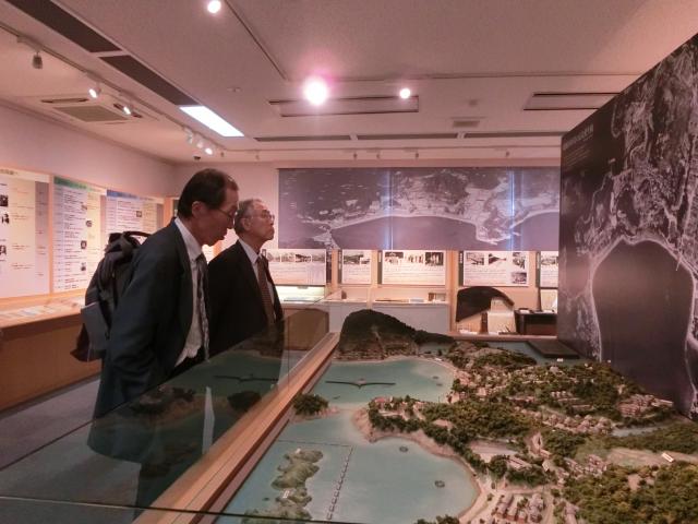 街の模型を年配の男性が二人並んで眺めている写真