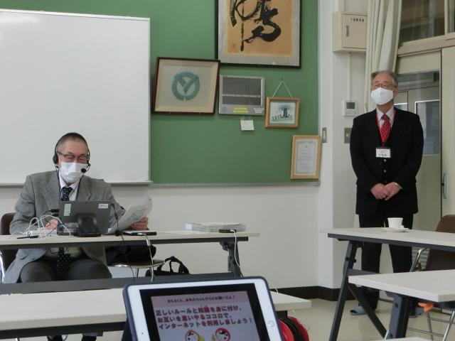 イヤホンマイクをした男性が机の目で書類を片手に作業している写真