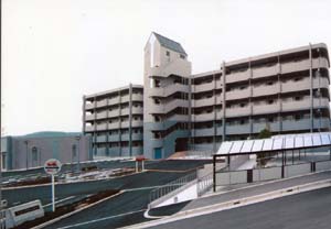 曇天の下たたずむ、5階建ての建物「三田市営住宅西山団地2号棟」の外観写真