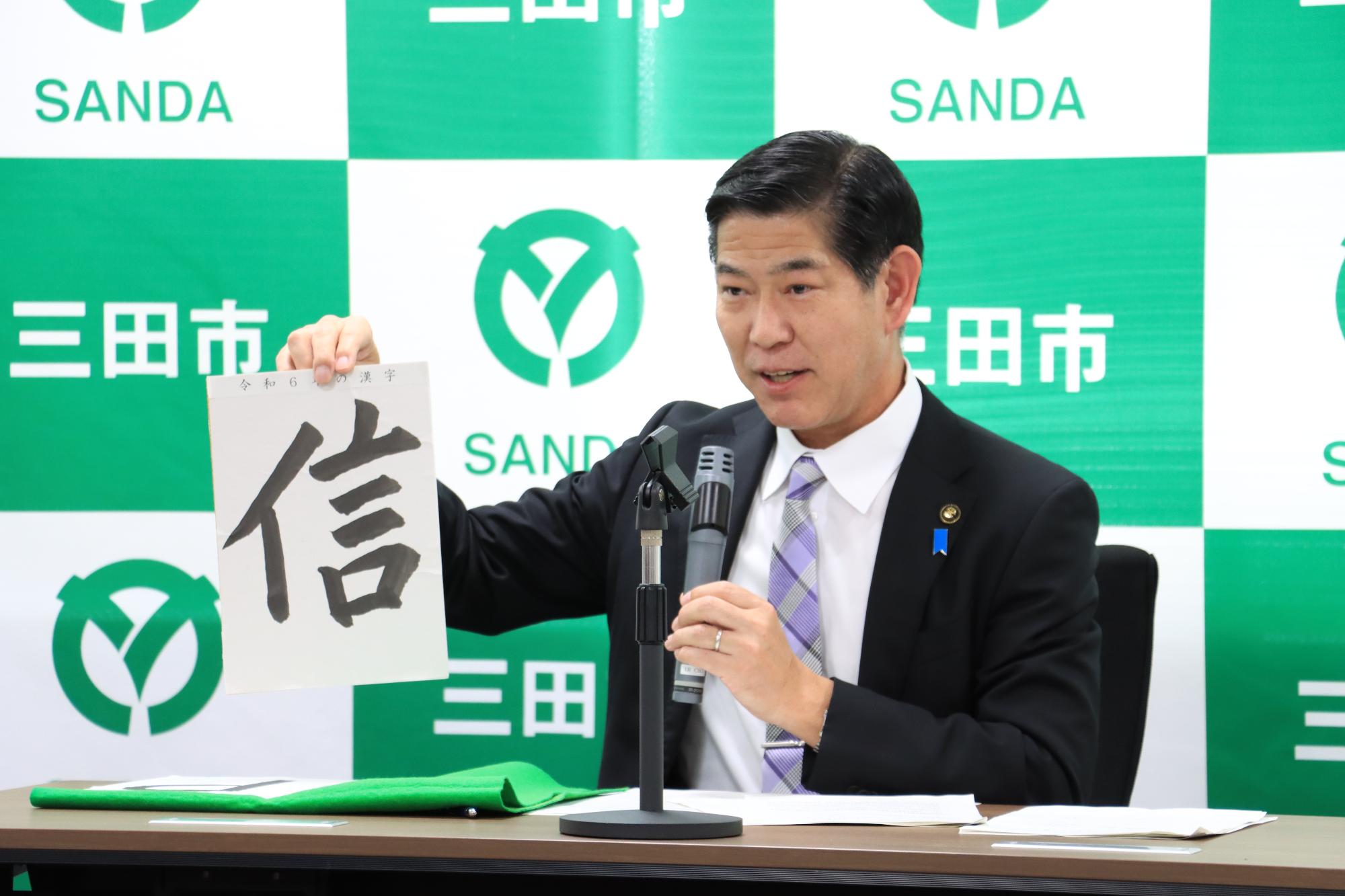 令和6年12月定例記者会見で今年を表す漢字を発表する田村市長の写真