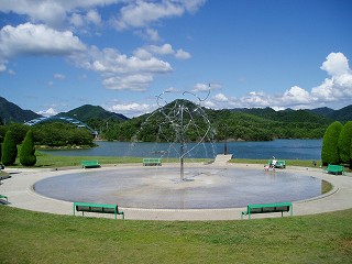 公園敷地内の噴水と千丈寺湖の遠景の写真