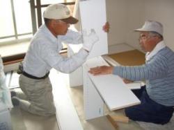 二人の年配の男性が一緒になって家具を組み立てている写真