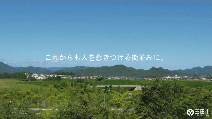 青空の下、遠くに山々が見える中、緑あふれる木々が辺り一面に広がっている写真 これからも人を惹きつける街並みに。三田市 sanda city